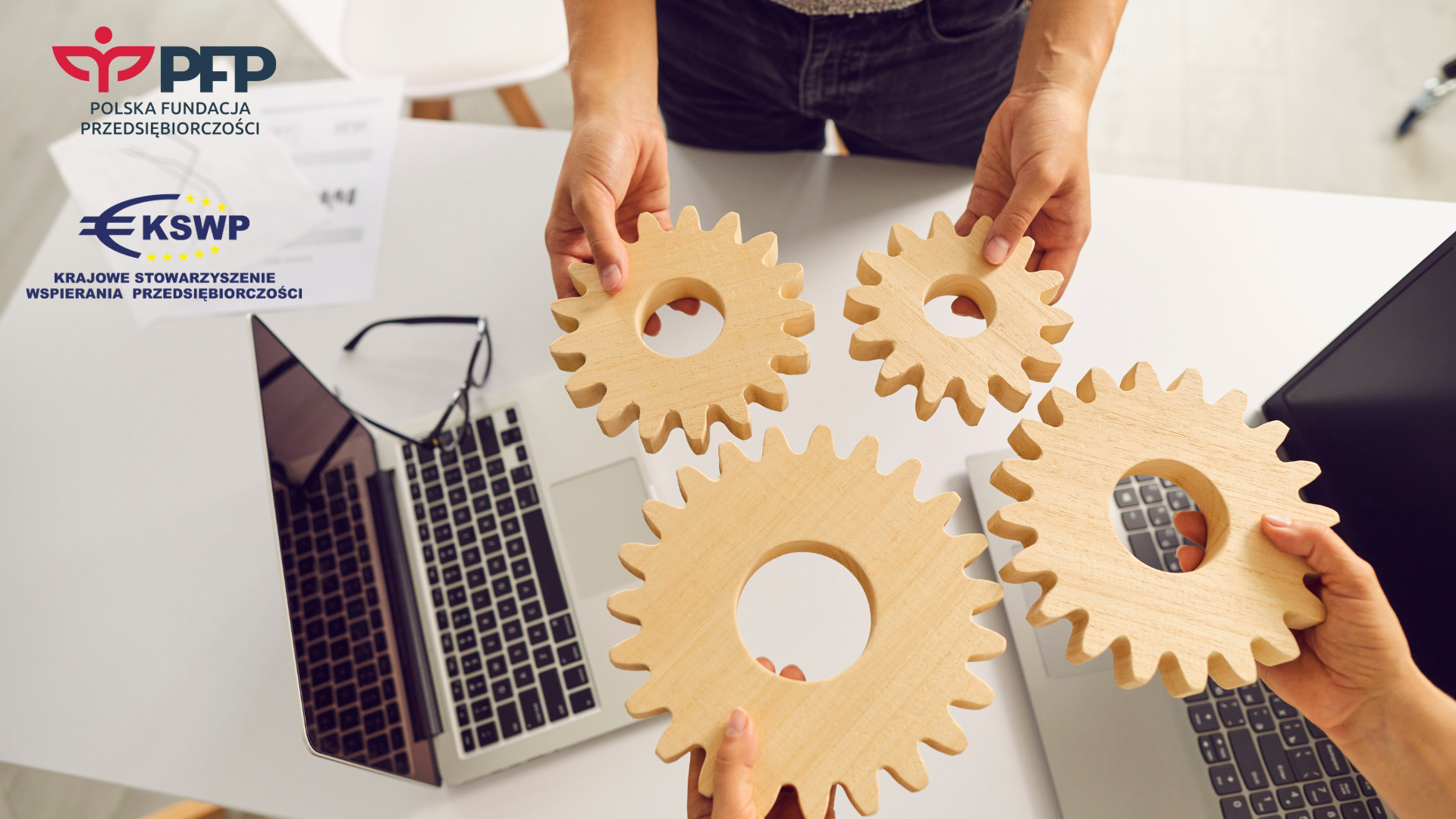 Ręce trzymające koła zębate nad biurkiem.1