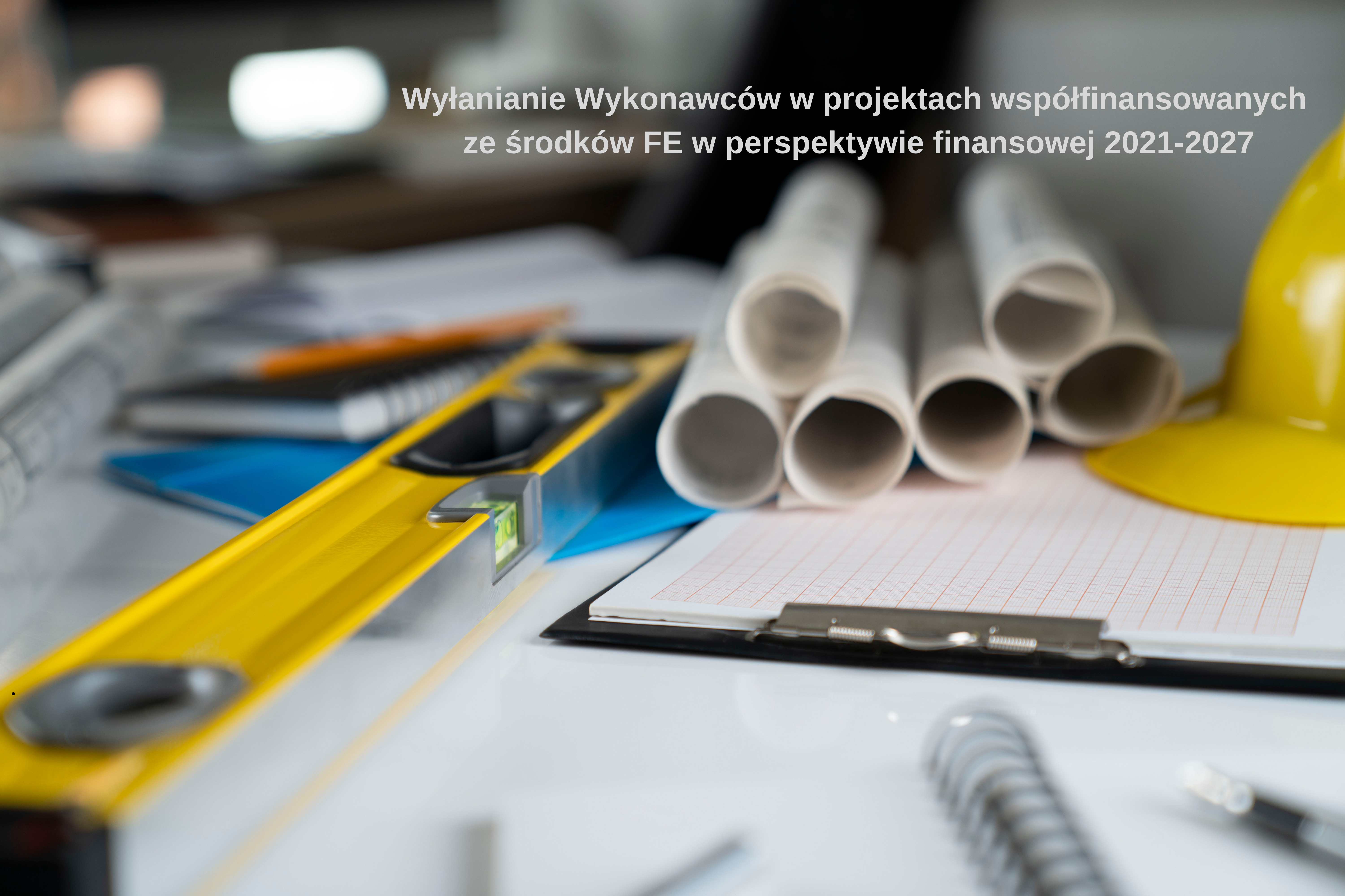 Obrazek przedstawia narzędzia, plany budowlane leżące na biurku.1