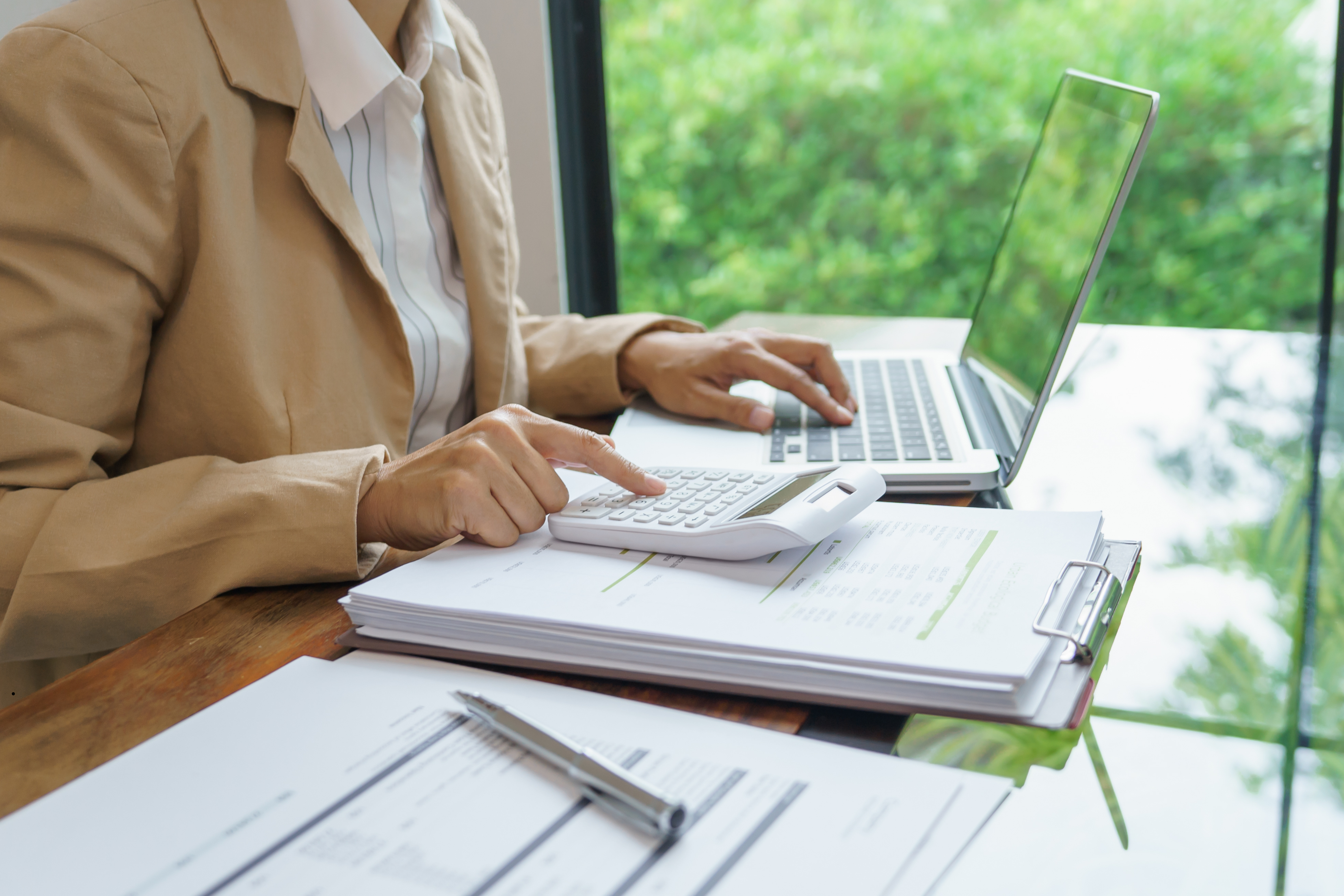 Osoba licząca dane na kalkulatorze i wprowadzająca je do laptopa.1